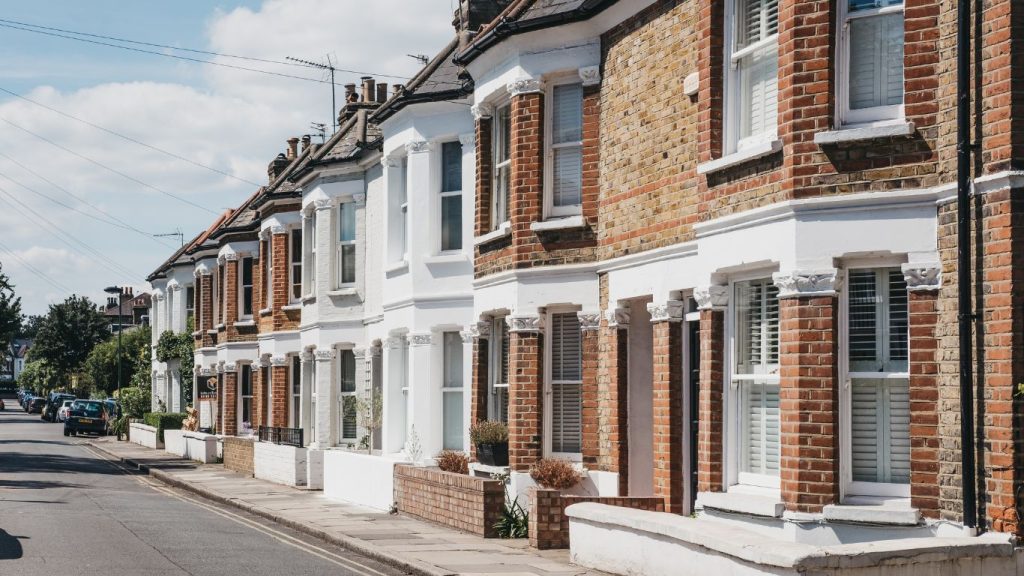 A row of terraced houses with bay windows, in bright sunshine.